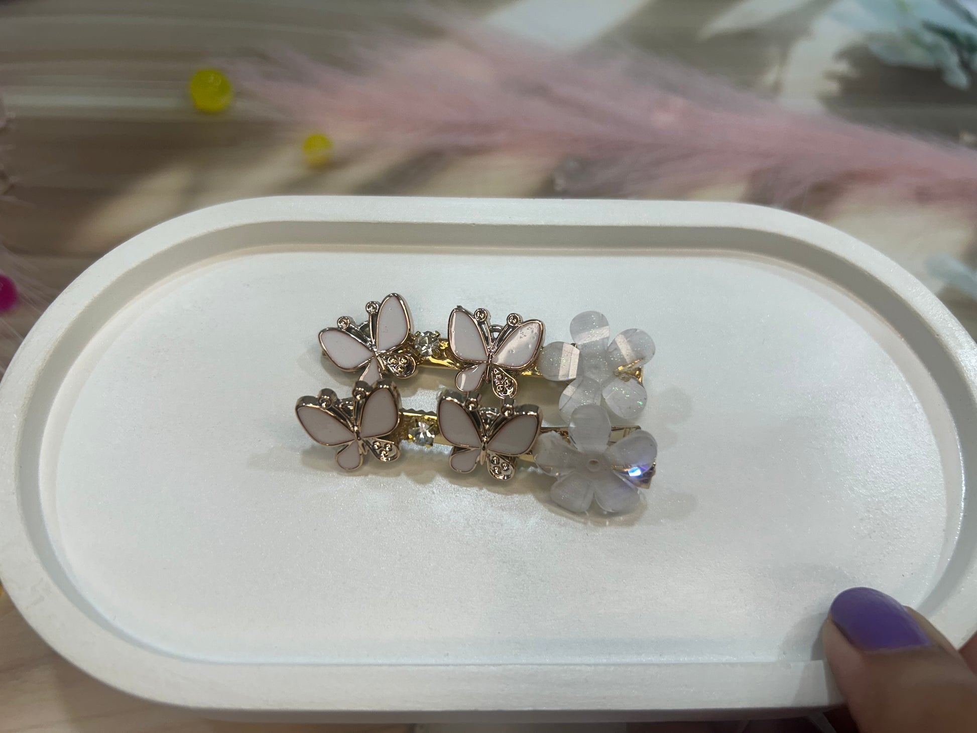 Pair of butterfly-shaped hair clip on a white display box with a blurred background.
