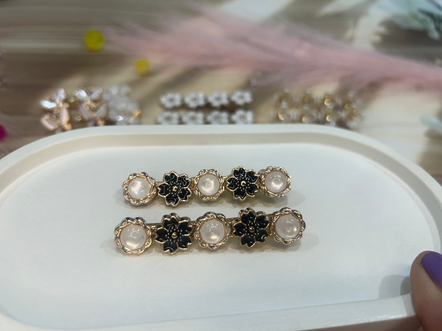 Pair of decorative hair clips with floral design on a white surface