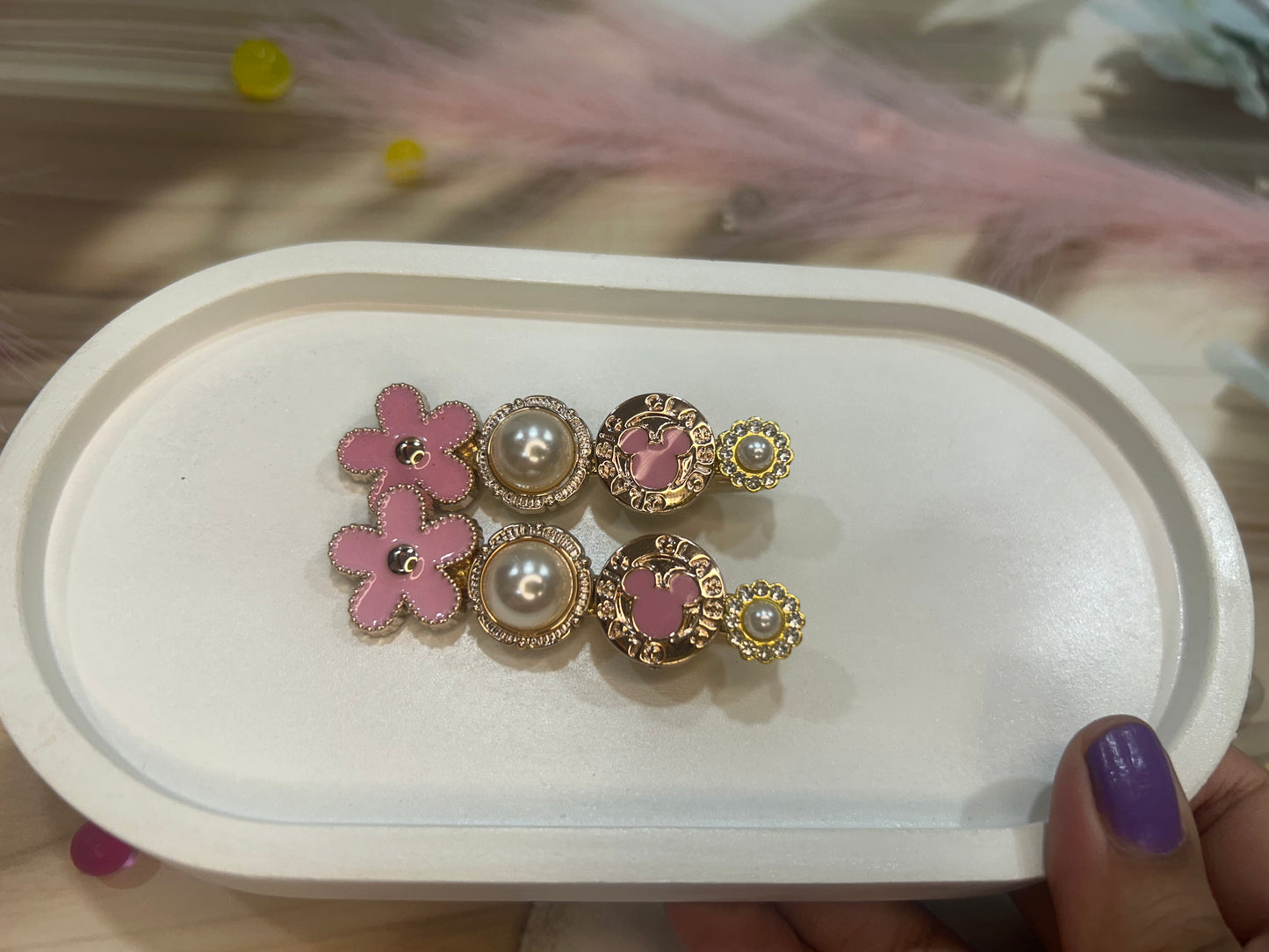 Pair of pink floral earrings with gold and pearl details on a white tray.