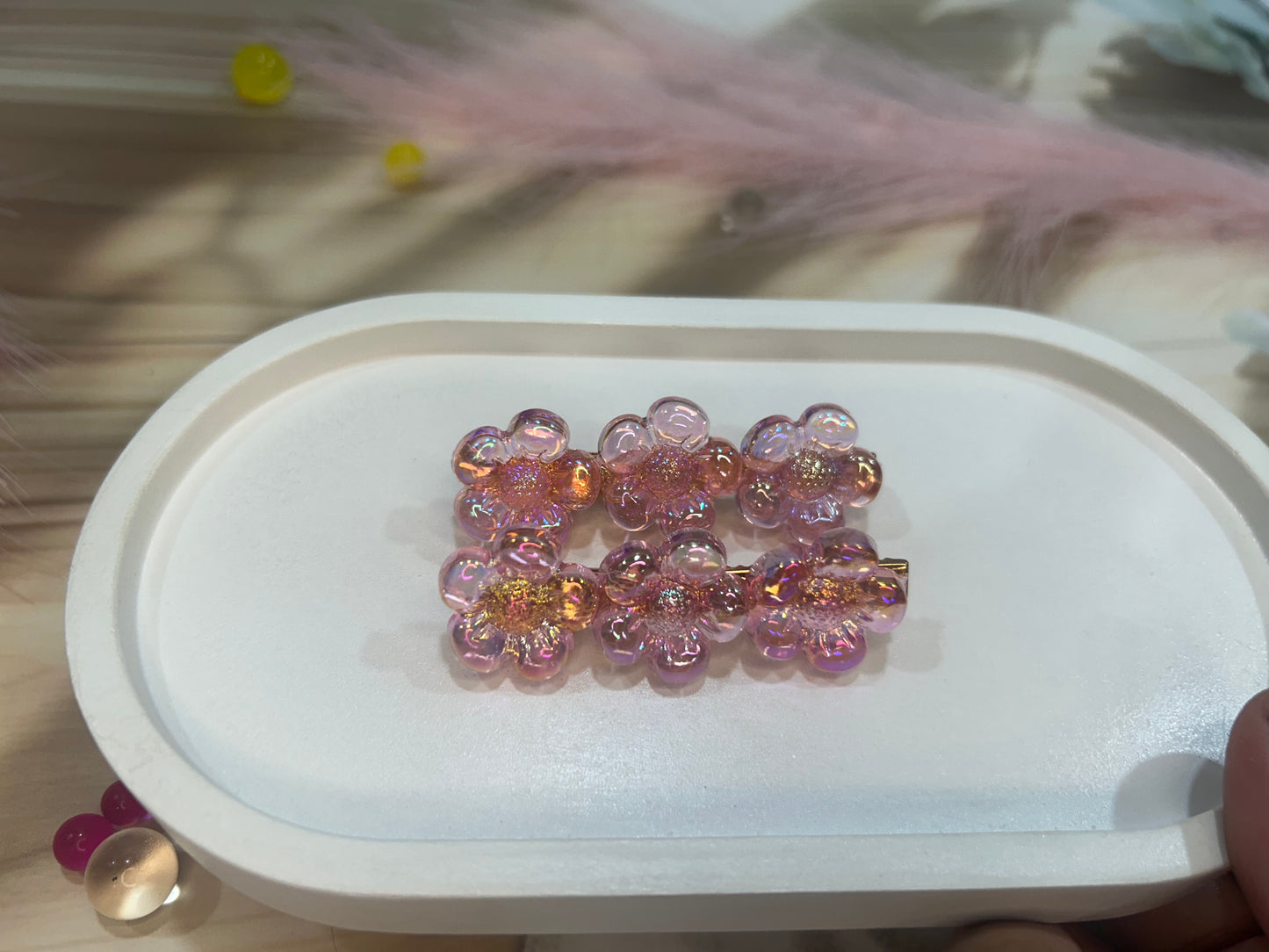 Decorative hair clip with pink and gold beads on a white tray.