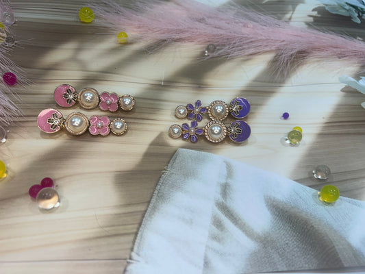 Pair of hair clip with pink and gold accents on a textured surface