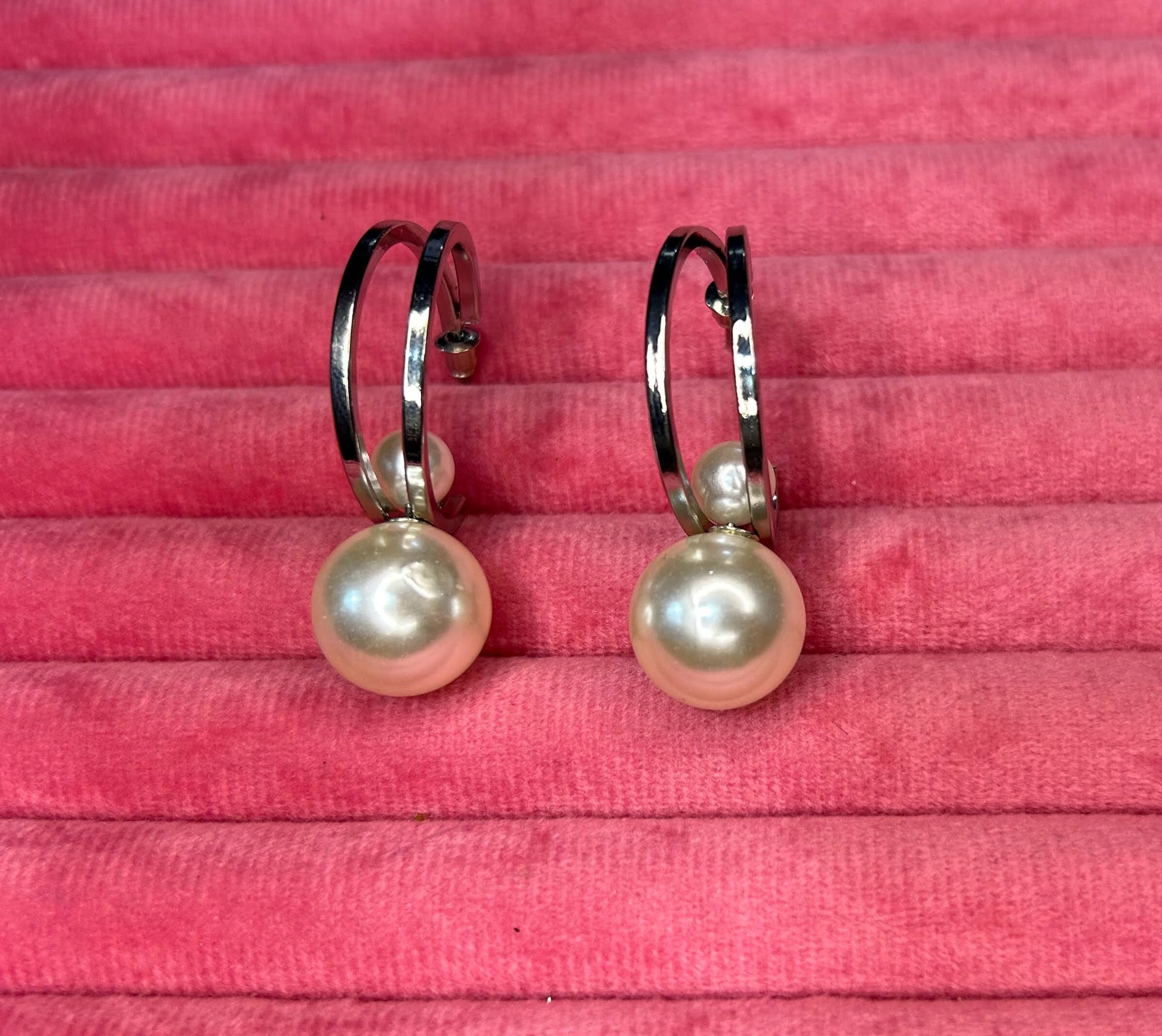 Pearl earrings on a pink textured background