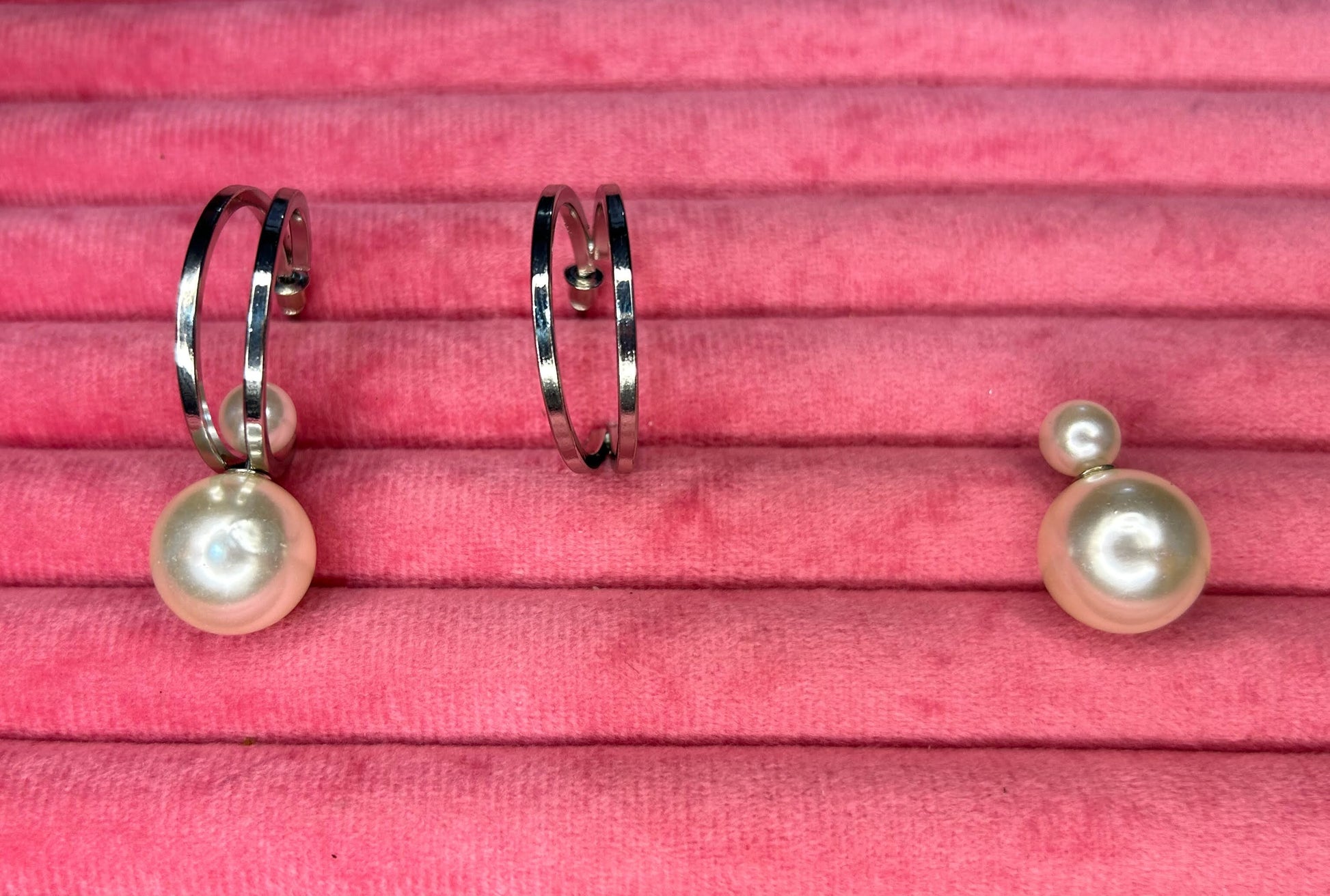 Pair of pearl earrings on a pink textured background