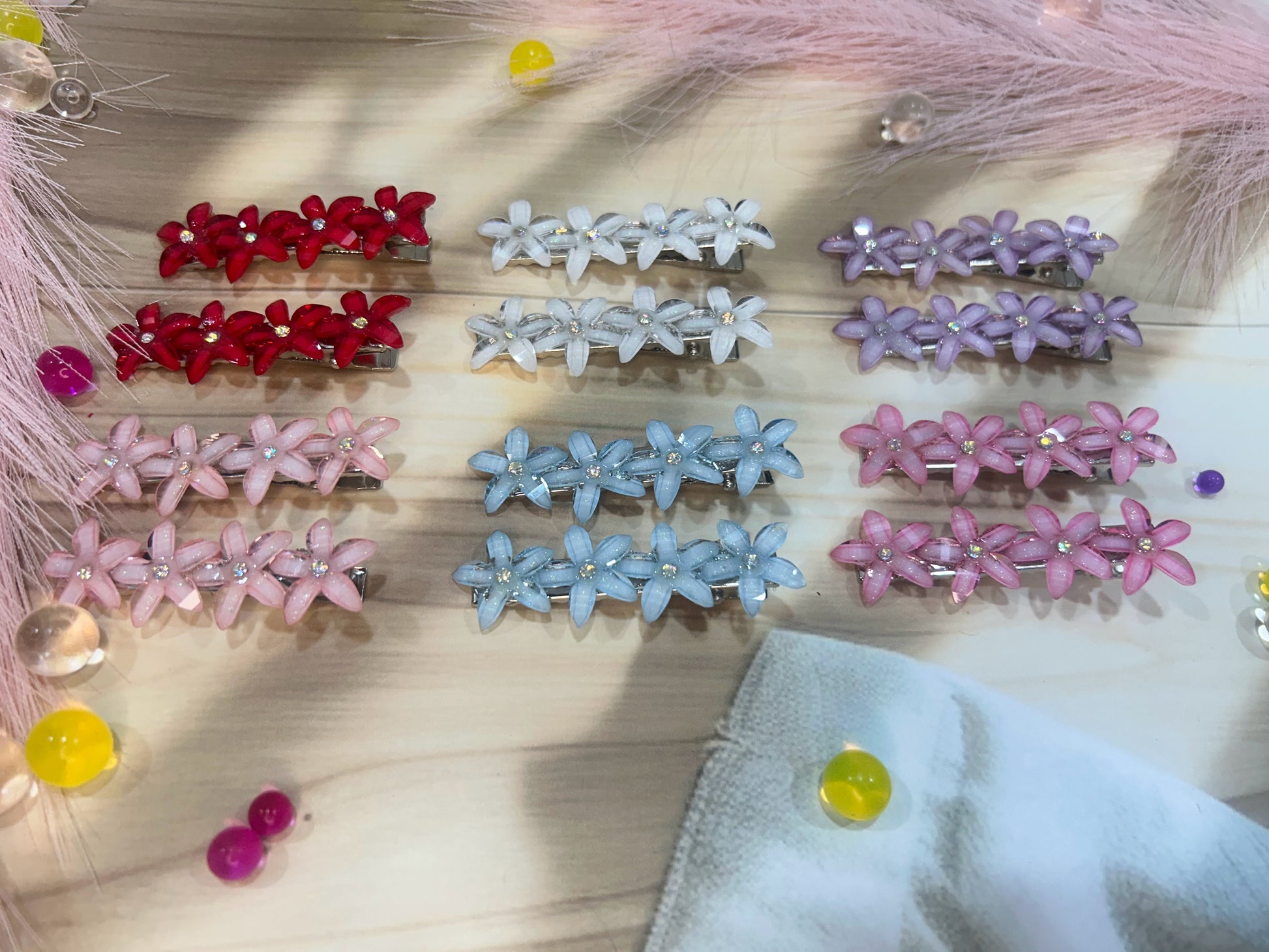 Colorful hair clips on a wooden surface with sunlight casting shadows.