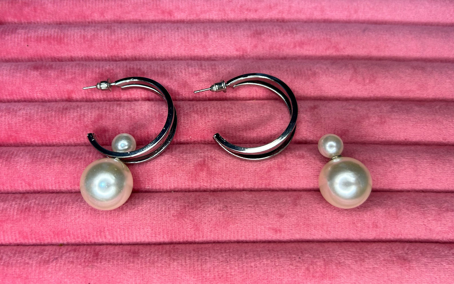 Pair of hoop earrings with pearl accents on a pink wooden surface