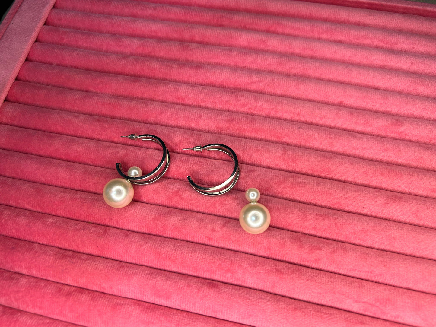 Pair of earrings with pearl accents on a pink pleated fabric background