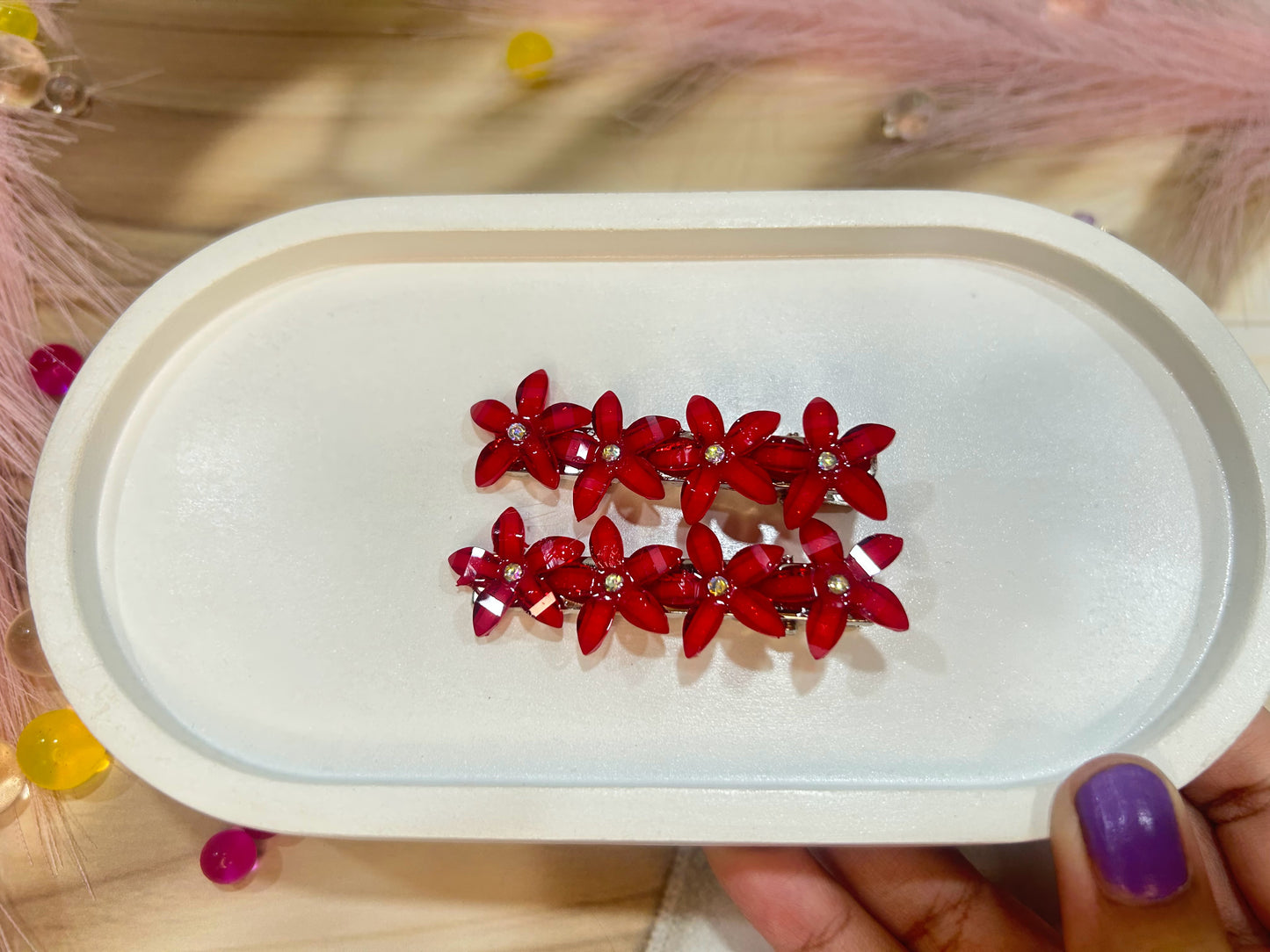 Red floral hair clip in a white case on a wooden surface
