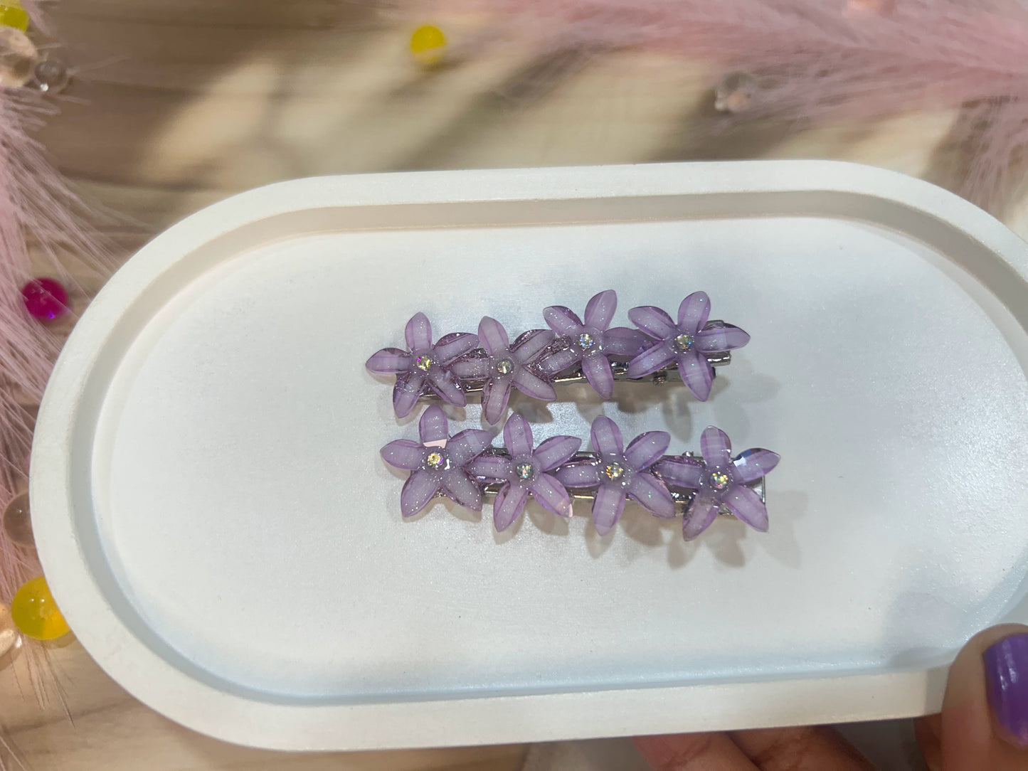Purple floral hair clips on a white tray with a blurred background