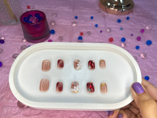 Set of nail designs in a display case held by a hand with purple nail polish.