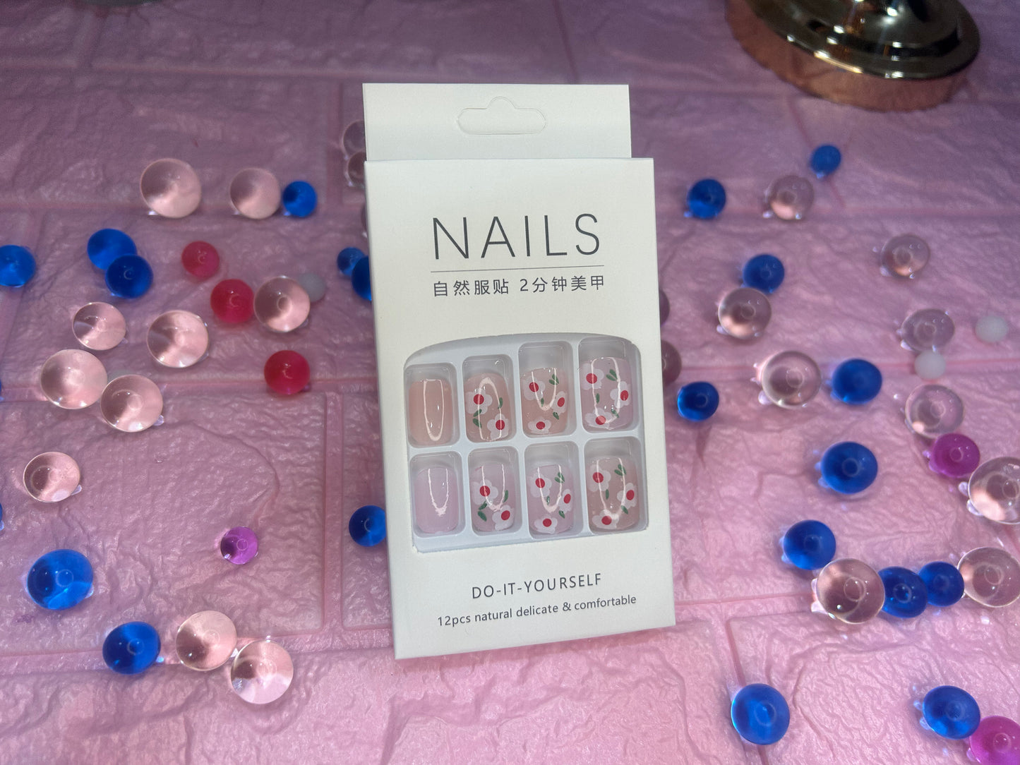 Nail art kit packaging with decorative nails on a textured surface