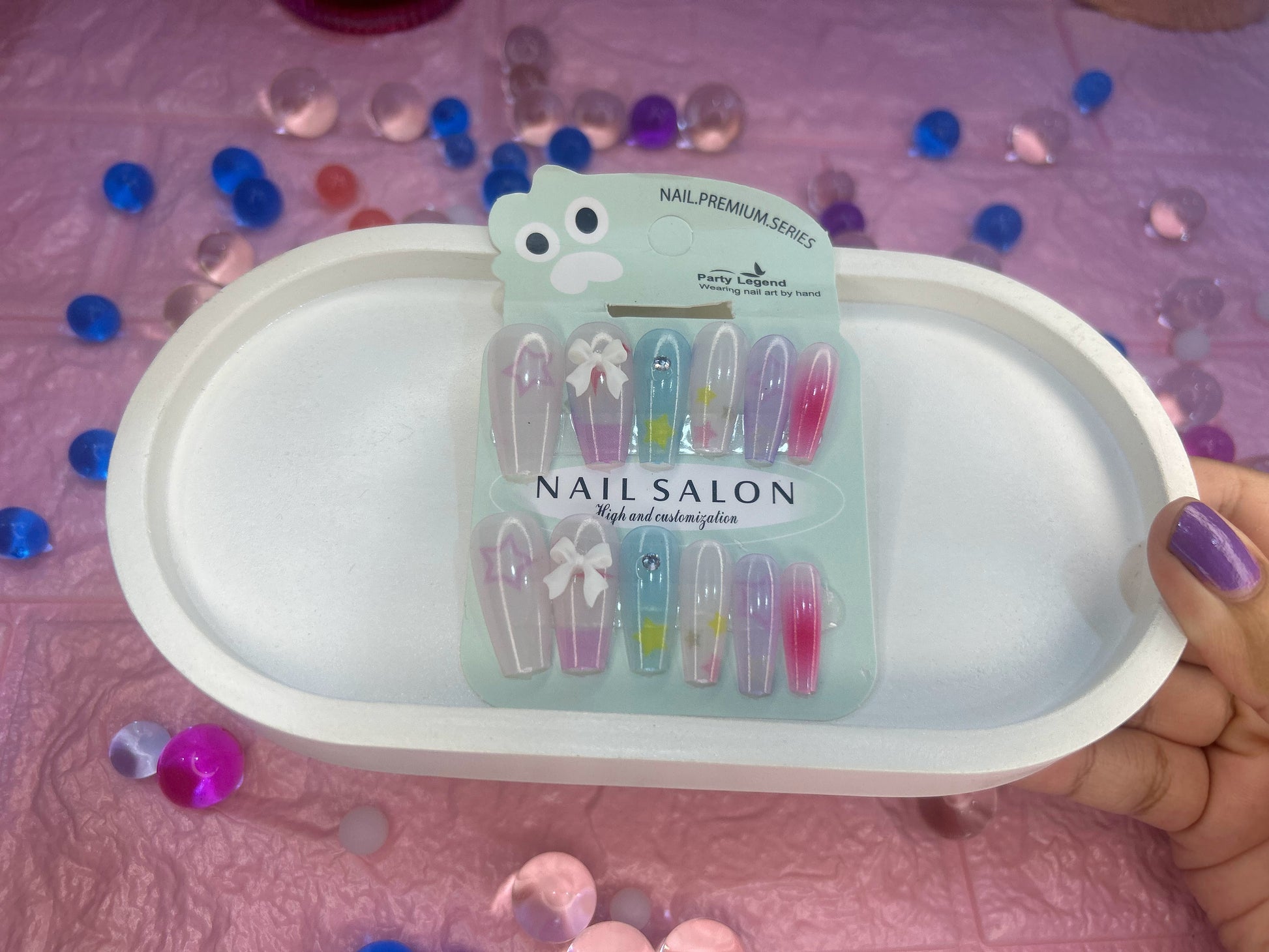 Pack of nail clips on a pink tray with decorative stones in the background
