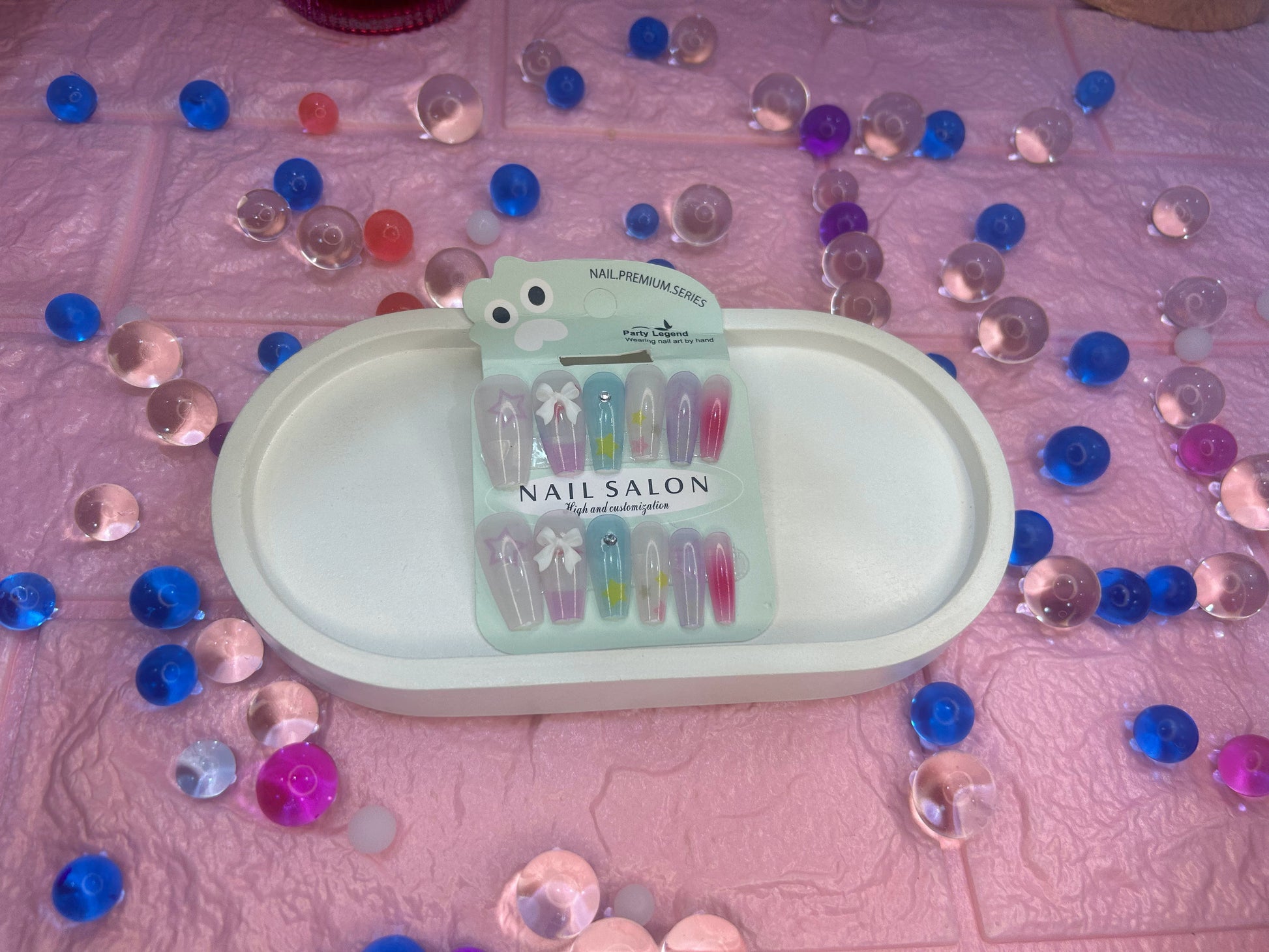Packaged nail salon tools on a pink surface with decorative stones.