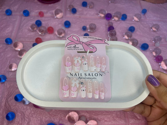 Pack of nail art decorations on a pink surface with scattered decorative items