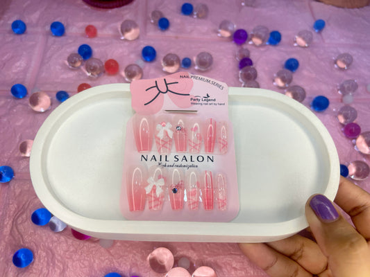 Nail art display with 'Nail Salon' packaging on a pink surface with decorative elements.