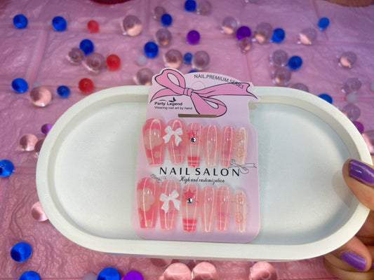 Packaged nail art items on a pink surface with decorative elements