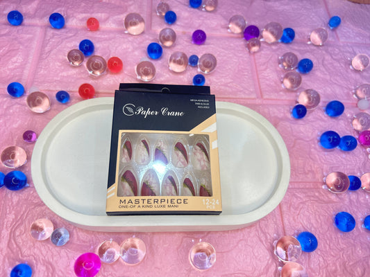 Box of false nails with 'Paper Crane' branding on a pink surface with decorative elements.