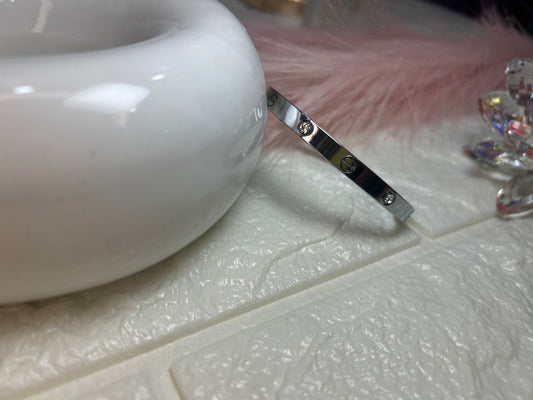 Silver bracelet on a textured white surface with a blurred background