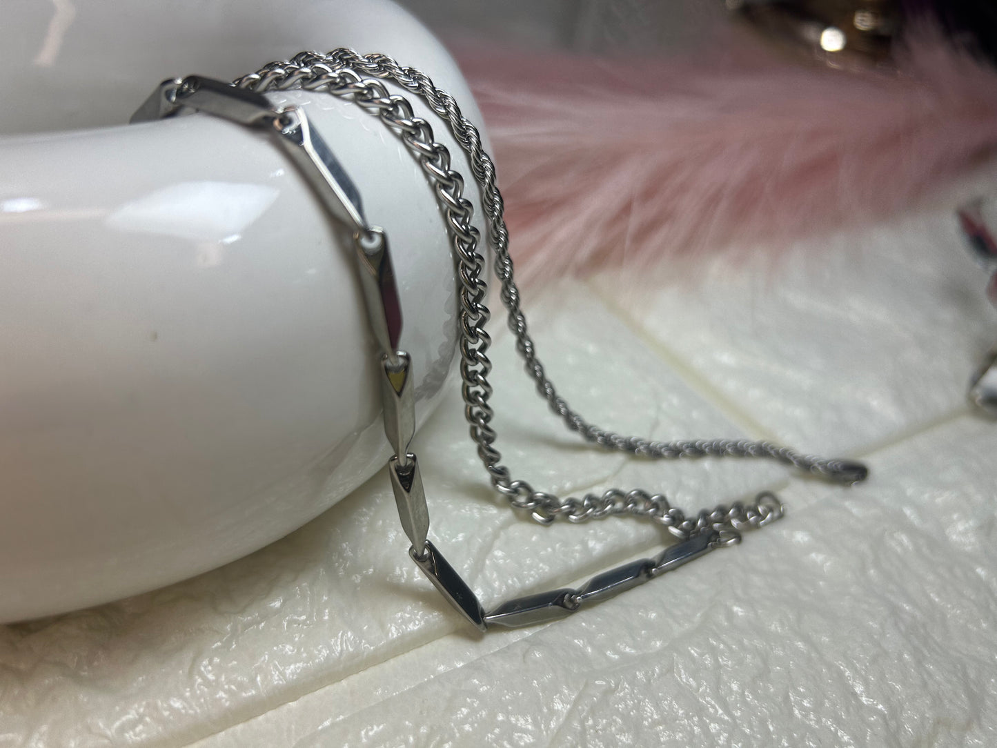 Silver bracelet on a white ceramic object with a soft pink background