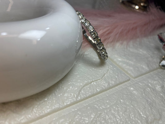 Silver ring with clear stones on a white ceramic surface
