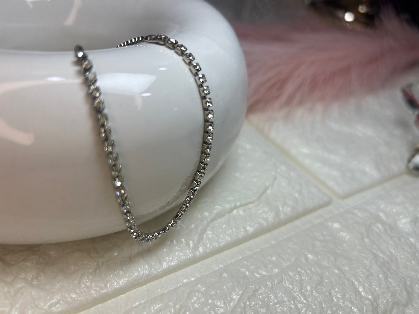 Silver chain on a white ceramic dish with a soft pink background