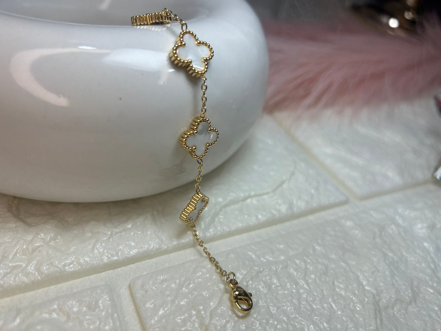 Gold bracelet on a white surface with a blurred background