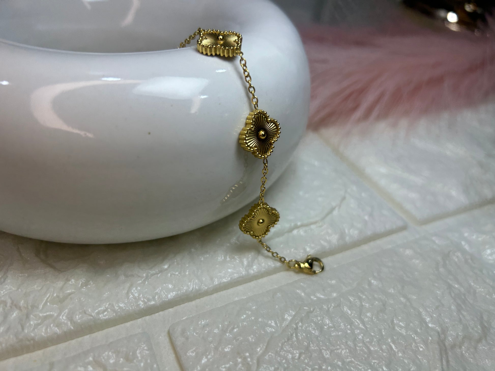 Gold bracelet on a white ceramic dish with a textured surface