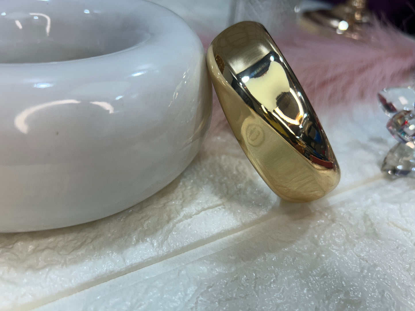 Gold ring on a textured white surface with a blurred background