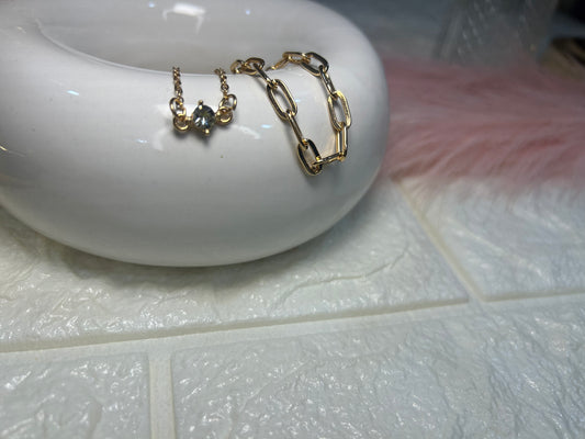 Gold chain and earring on a white ceramic dish with a blurred background