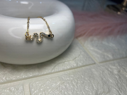 Gold necklace with a pendant on a white ceramic dish