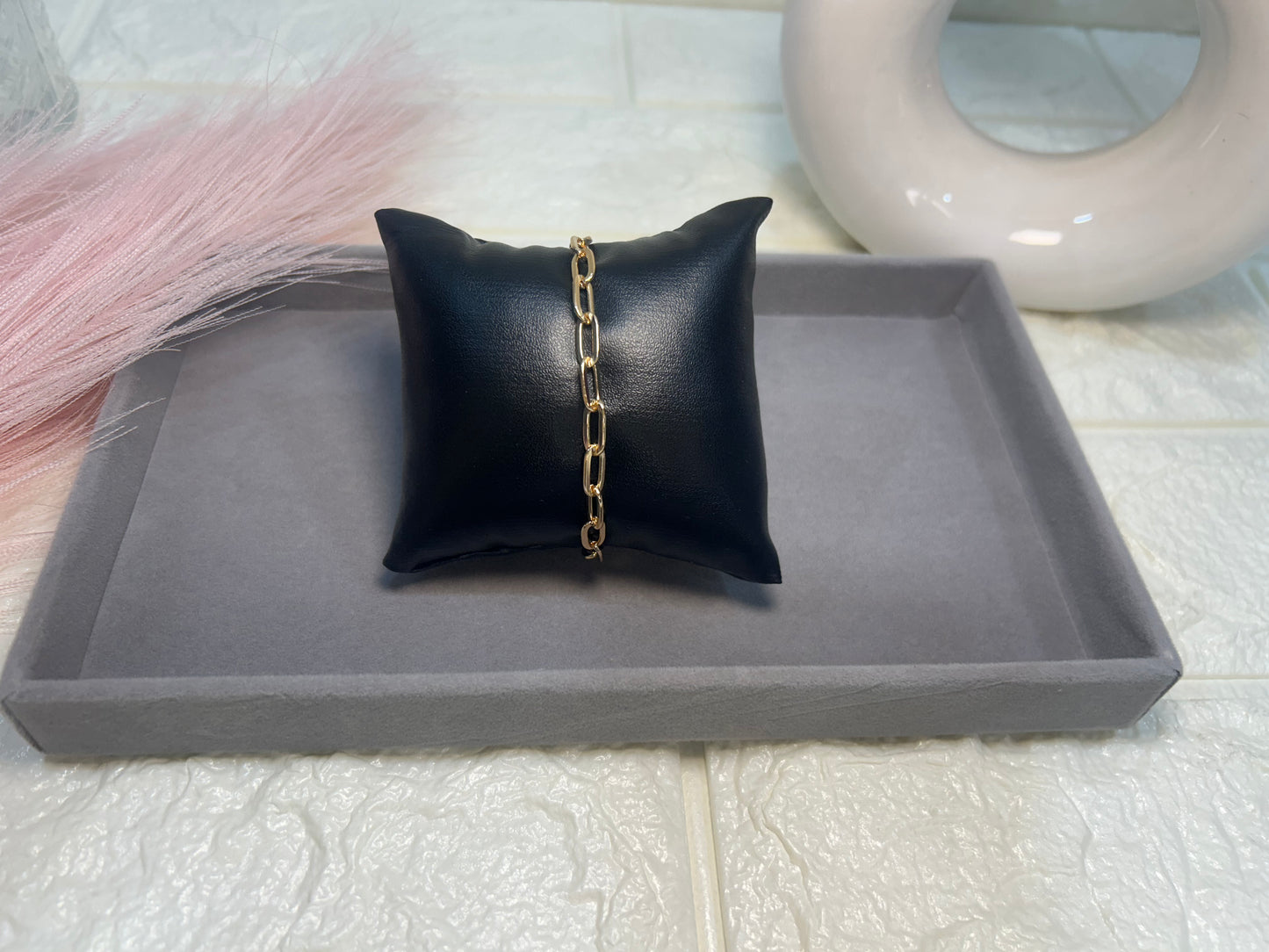 Black jewelry pillow with a gold chain on a gray tray
