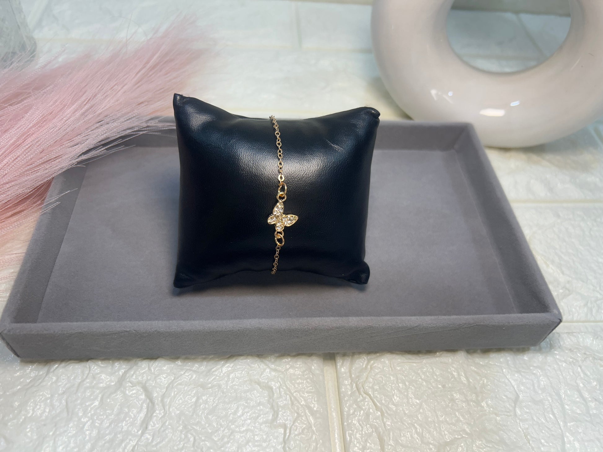 Black leather pillow with a gold necklace on a gray tray