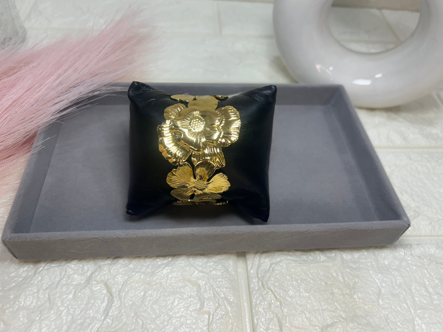 Black pillow with gold floral design on a gray tray