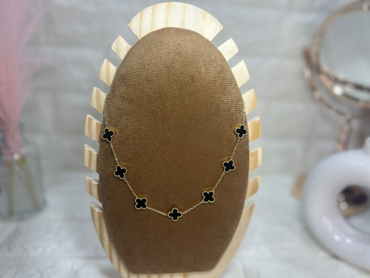 Necklace with black clover-shaped pendants on a brown jewelry display.