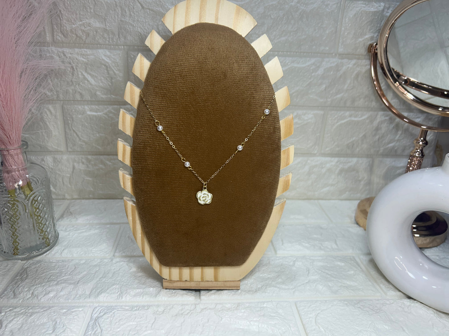 Necklace on a brown velvet stand with decorative elements in the background