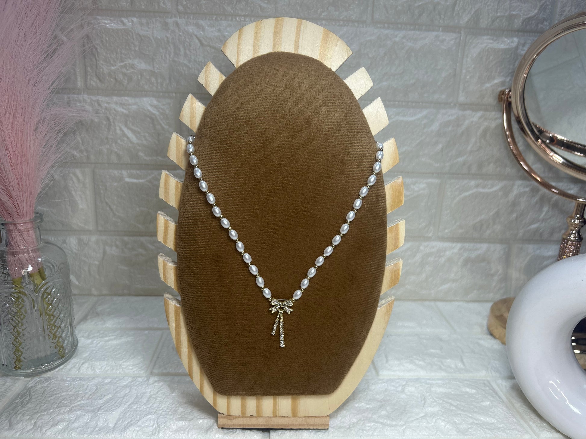 Pearl necklace on a brown velvet display stand with a decorative background.