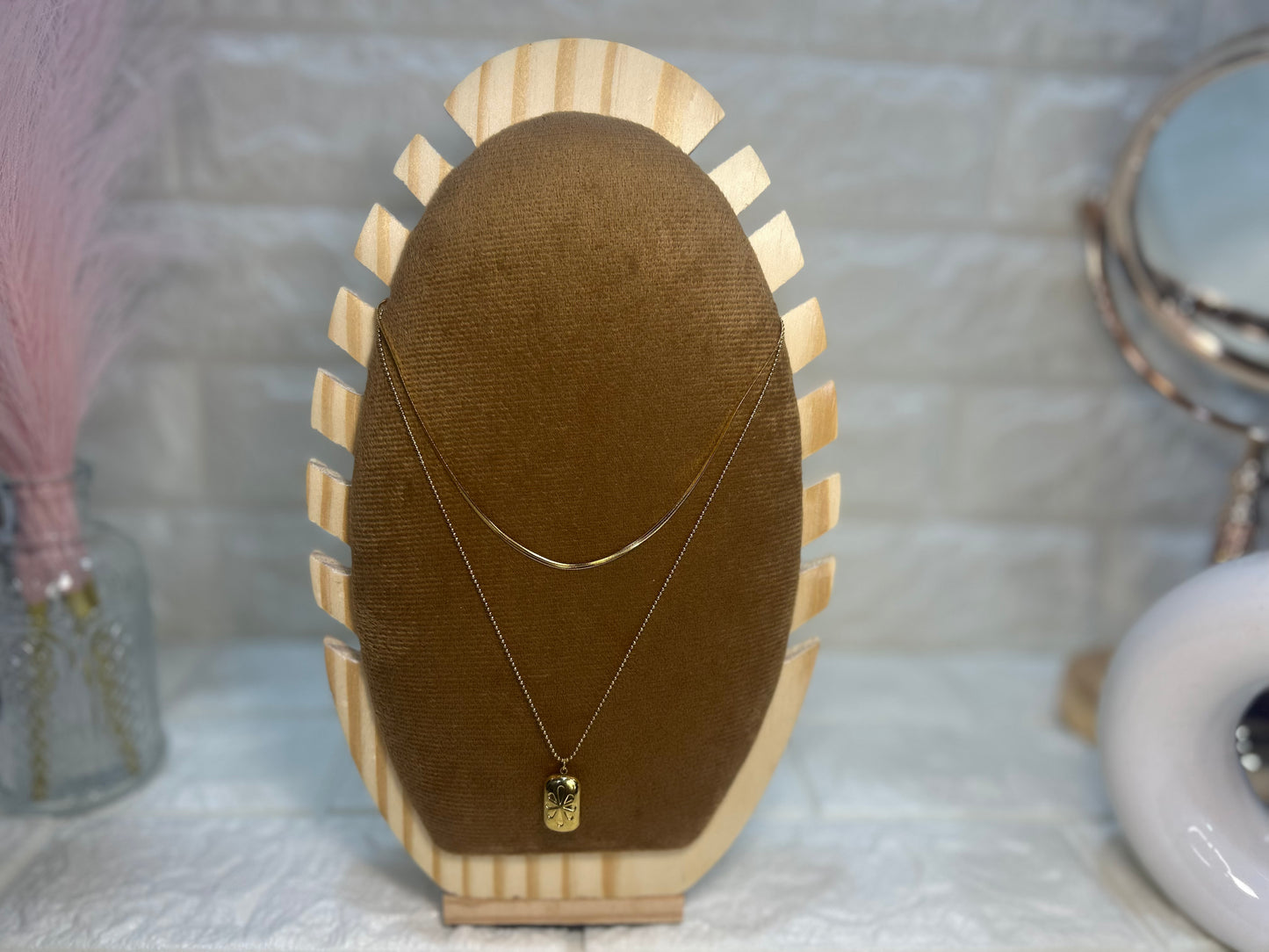 Necklace with a pendant on a wooden display stand against a neutral background