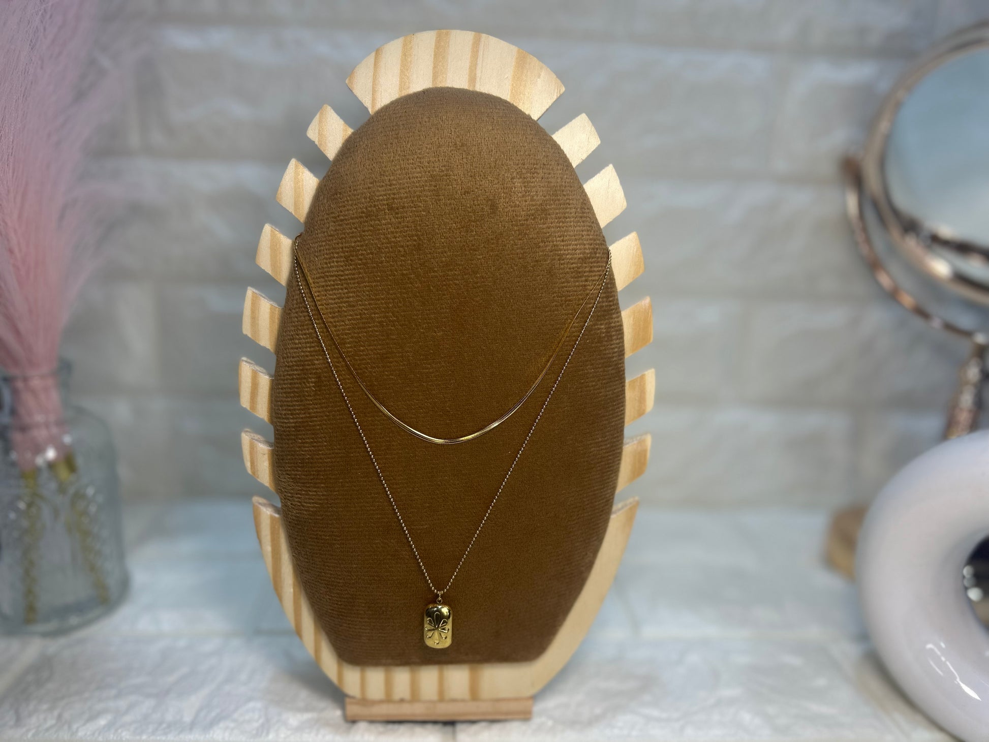 Necklace with a pendant on a wooden display stand against a neutral background