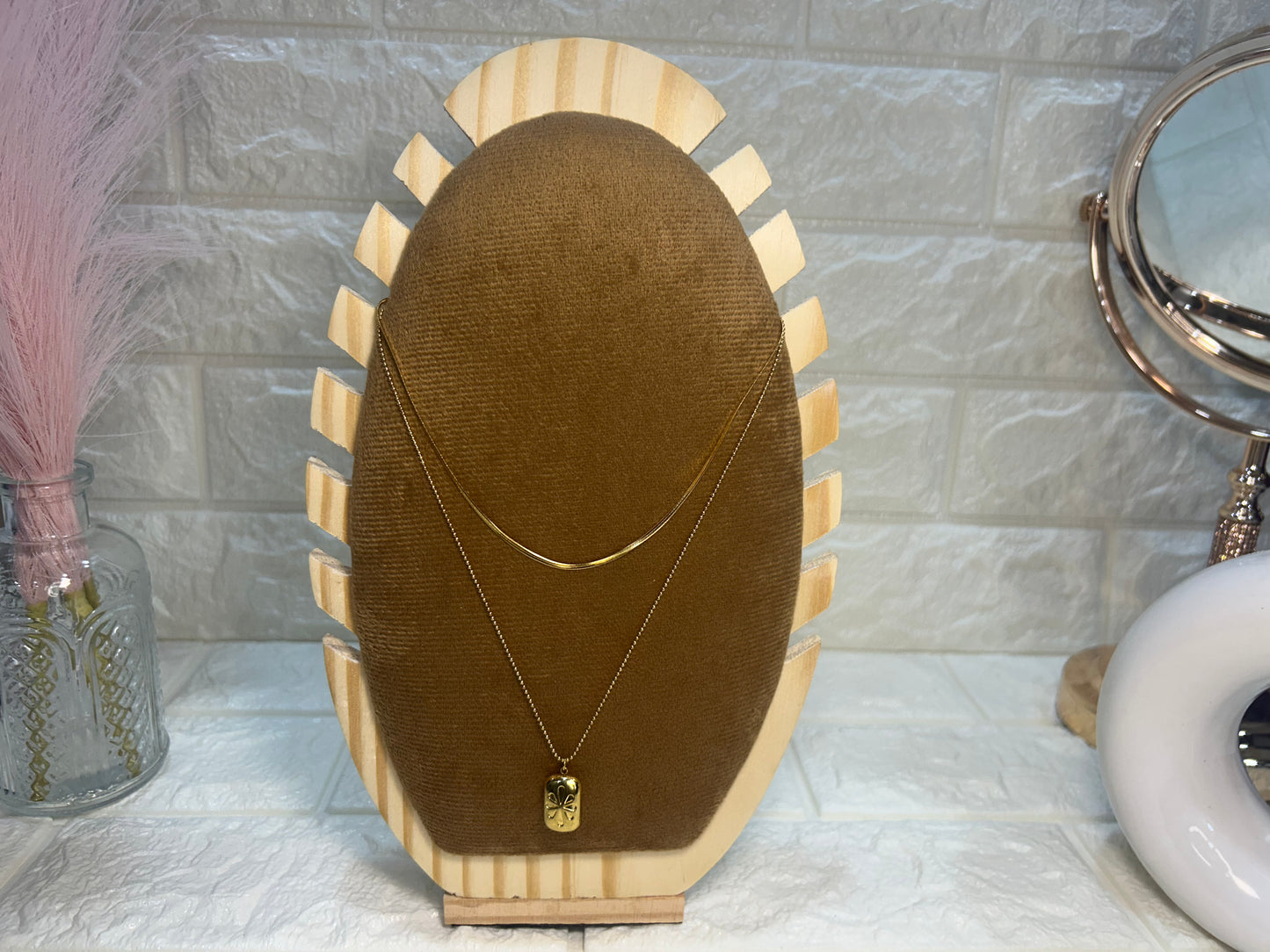 Necklace on a brown velvet stand with a marble wall background