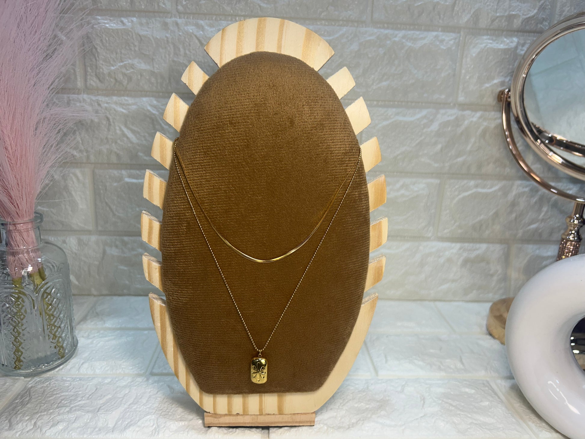 Necklace on a brown velvet stand with a marble wall background