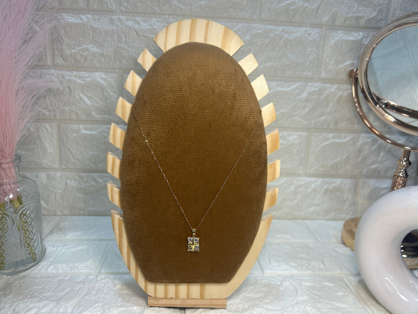 Necklace on a brown velvet stand with a marble-patterned wall in the background