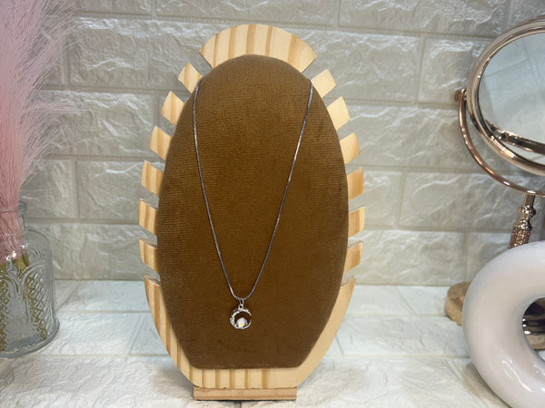 Necklace on a wooden stand with a marble wall background