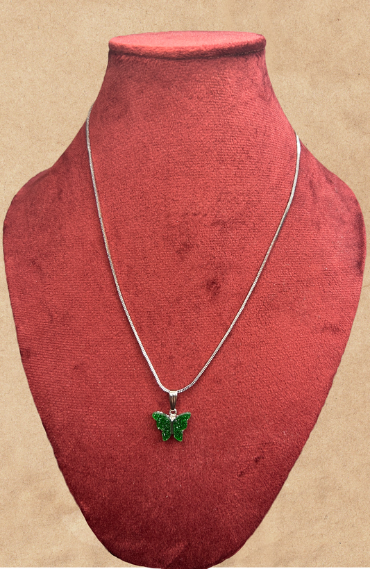 Necklace with a green butterfly pendant on a red velvet stand against a beige background