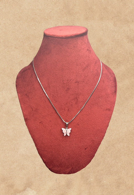 Silver butterfly pendant necklace on a red velvet mannequin bust against a beige background