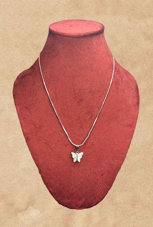 Butterfly necklace on a red mannequin bust against a beige background
