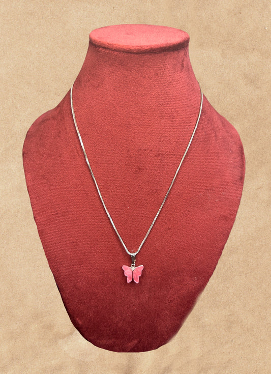 Necklace with a pink butterfly pendant on a red mannequin bust against a beige background