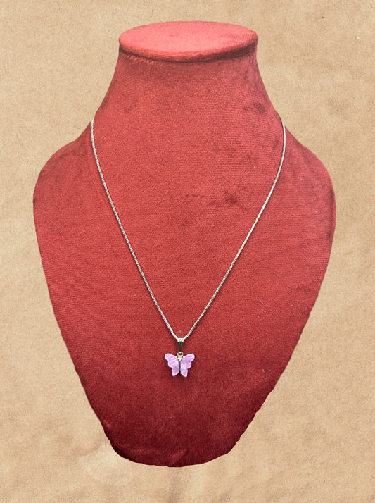 Butterfly pendant necklace on a red velvet mannequin bust against a beige background