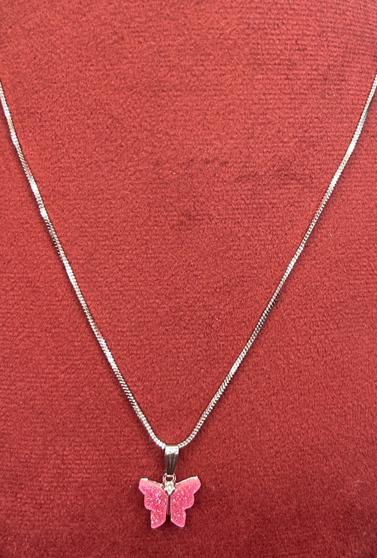 Pink butterfly pendant necklace on a red mannequin bust.