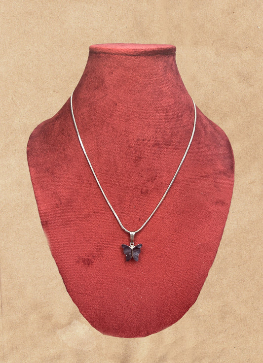 Necklace with a butterfly pendant on a red velvet stand against a beige background
