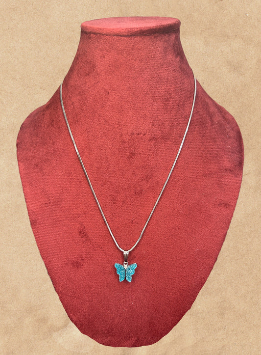 Necklace with a blue butterfly pendant on a red velvet mannequin bust.