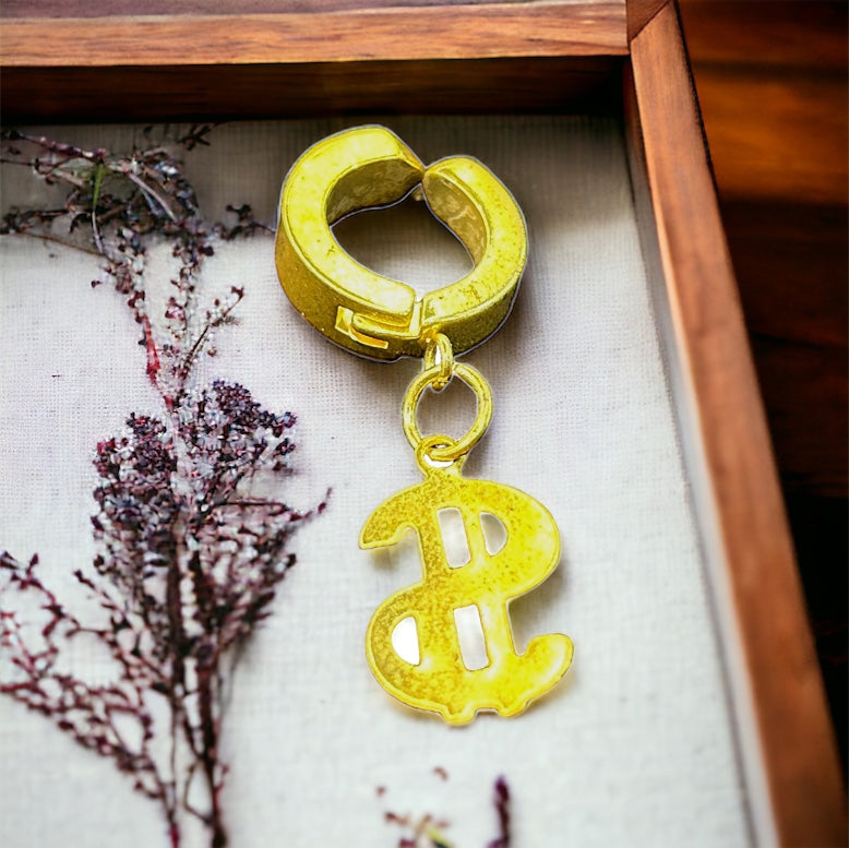 Yellow hoop earring with dollar sign charm on a neutral background